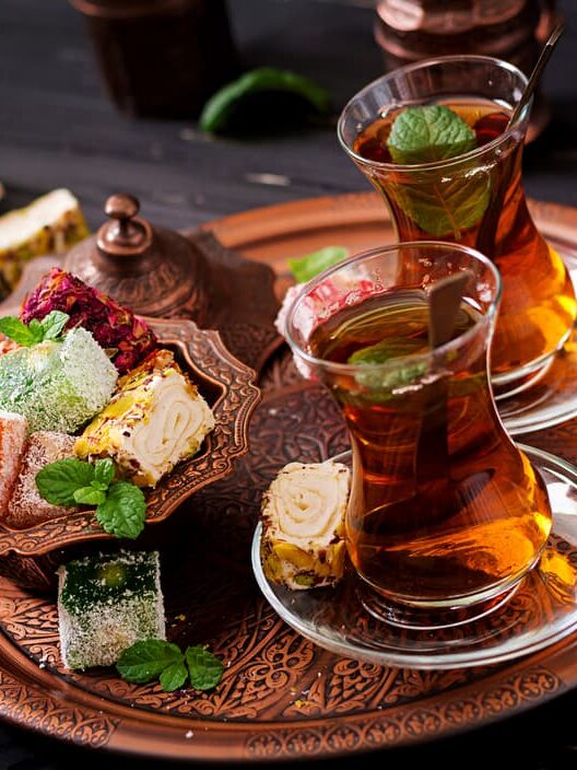 Fresh cocktails in glass tumblers and specialised vegan deserts on the side, sitting on an engraved wooden round serving tray